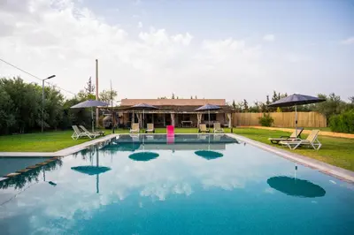 a swimming pool with blue water in front of a house at Oléa villa & lodge in Marrakech