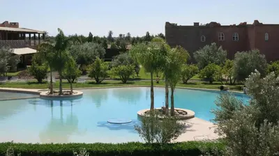 a swimming pool with palm trees and a castle in the background at Villa Yasmine Marrakech in Marrakech
