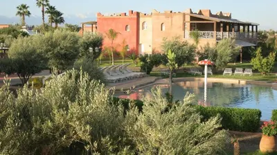 a building with a fountain in front of a lake at Villa Yasmine Marrakech in Marrakech