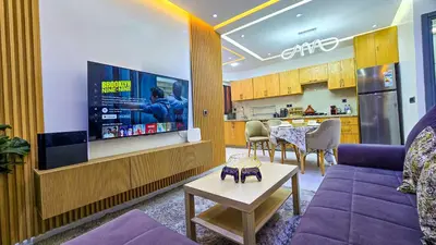 a living room with a couch and a tv at Appartement Chic et Confortable, Netflix, PS4 & Wi-Fi Centre Marrakech in Marrakech