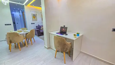 a living room with a table with a laptop on it at Appartement Chic et Confortable, Netflix, PS4 & Wi-Fi Centre Marrakech in Marrakech