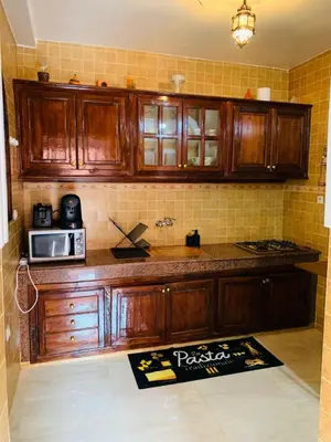 a kitchen with wooden cabinets and a microwave at 3 bedroom duplex with swimming pool in Marrakech