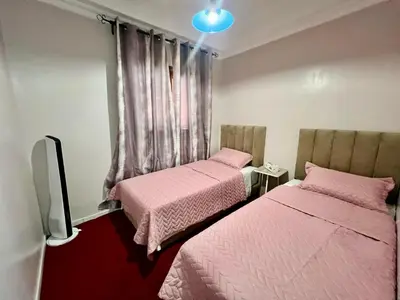 two beds in a room with pink sheets at appartement Airport Guests Marrakech in Marrakech