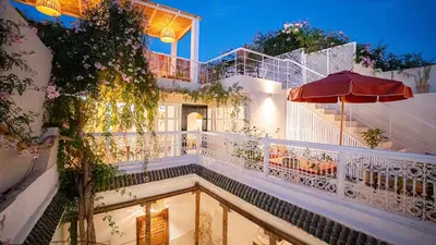 a building with a swimming pool and an umbrella at Riad Dar Zioui in Marrakech