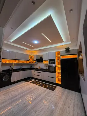 a large kitchen with white cabinets and black appliances at Housna B&B Marrakesh in Marrakech