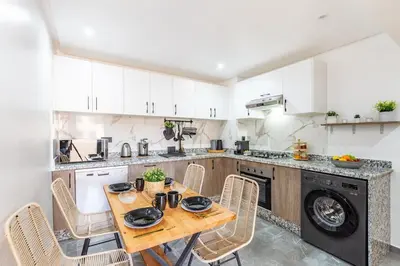 a kitchen with a wooden table and chairs at Appartement Haut de Gamme avec Piscine Privée et Grande Terrasse in Marrakech