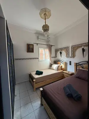 a bedroom with two beds and a chandelier at RIAD SAAD Marrakech in Marrakech