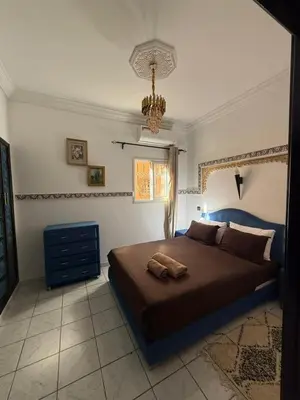 a bedroom with a large bed and a chandelier at RIAD SAAD Marrakech in Marrakech