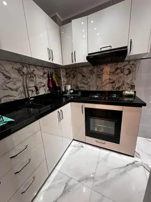 a kitchen with white cabinets and a sink and a stove at Appartement Familial Spacieux & Moderne - Confort et Style au Rendez-vous ! in Marrakech