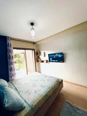 a bedroom with a bed and a tv on the wall at Cozy RC golf view pool & Atlas fiber optic 2 bedrooms in Marrakech