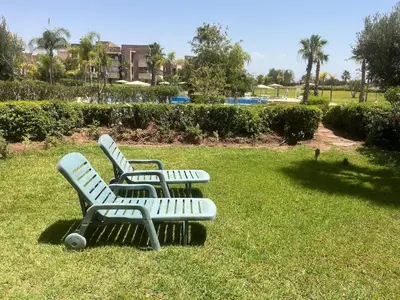 three green park benches sitting in the grass at Cozy RC golf view pool & Atlas fiber optic 2 bedrooms in Marrakech