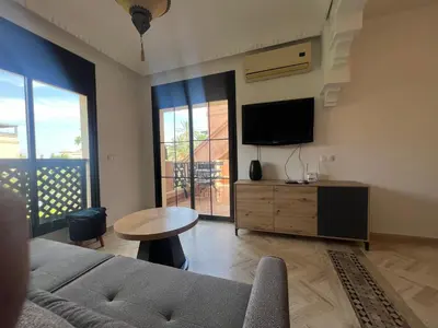 a living room with a couch and a table and a tv at L'oasis d'Atlas Golf Resort in Marrakech