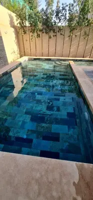 a swimming pool with blue tiles on the ground at Villa 5 chambres targa in Marrakech