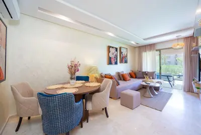 a living room with a table and a couch at Vue Piscine et Golf Luxueux rez de jardin in Marrakech
