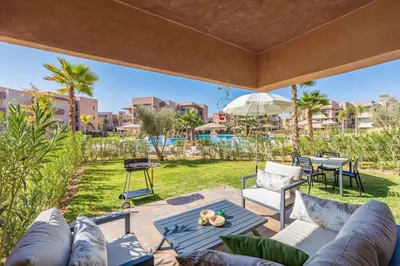a patio with a couch and a table and chairs at Vue Piscine et Golf Luxueux rez de jardin in Marrakech