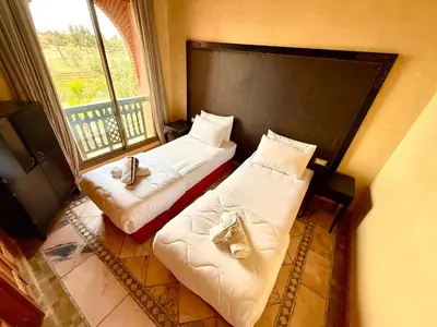 two beds in a room with a window at la palmeraie village 3 in Marrakech