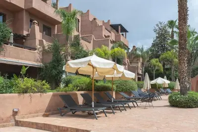 a row of lounge chairs with umbrellas in front of a building at Agdal Prestige in Marrakech