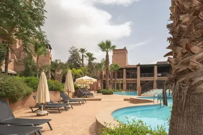 a resort with a swimming pool with chairs and umbrellas at Agdal Prestige in Marrakech