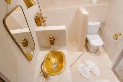 a bathroom with a gold sink and a toilet at Refuge blanc terrasse priveee a cite de Majorelle in Marrakech
