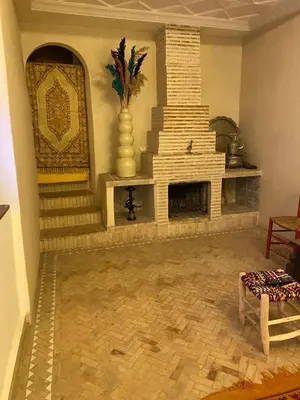 a living room with a stone fireplace and a staircase at Riad khalid zrika in Marrakech