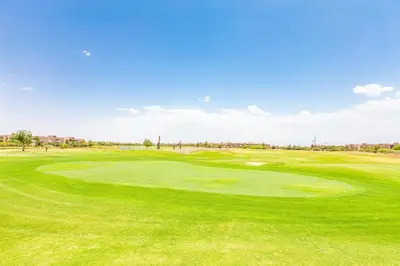 a green golf course with a hole in the grass at Opulent 3BR apartment, pool view in Marrakech