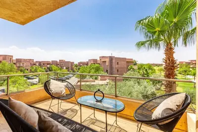 a balcony with chairs and a palm tree at Opulent 3BR apartment, pool view in Marrakech