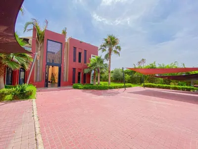 a red building with palm trees in front of it at villas route d amzmiz in Marrakech