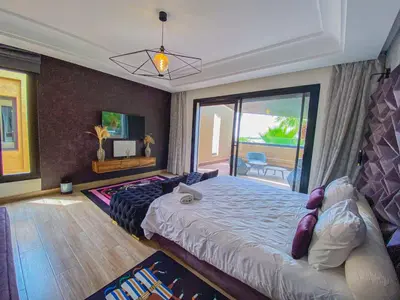 a bedroom with a large bed and a balcony at villas route d amzmiz in Marrakech