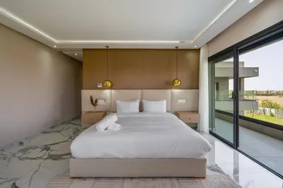a bedroom with a large bed and a large window at Villa Arbia - Piscine - 5BDR - Fitness - Ping-Pong in Sraghna