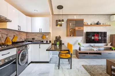 a kitchen with white cabinets and a table and a sink at Luxury CINÉMA-BEDROOM AK38 FullHD Guéliz-TopCenter in Marrakech