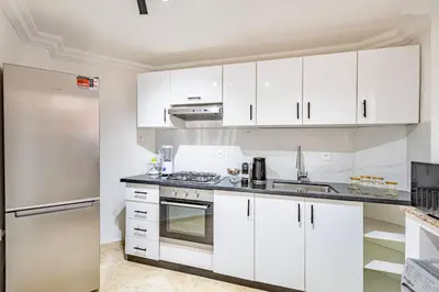a kitchen with white cabinets and a stainless steel refrigerator at Modern Apartment Gueliz City Center in Marrakech