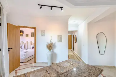 a living room with a table and a bedroom at Manahil Modern Apartment Gueliz City Center in Marrakech