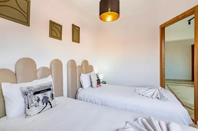 two beds in a room with white walls at Manahil Modern Apartment Gueliz City Center in Marrakech