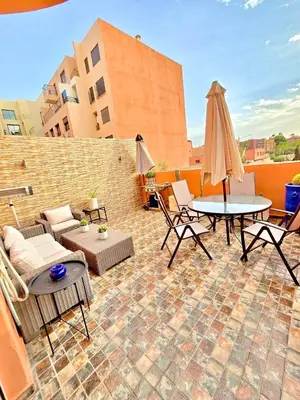 a patio with a couch and a table and umbrella at Joli et chic Appartement à Marrakech - balcon privé et confort in Oulad Akkou