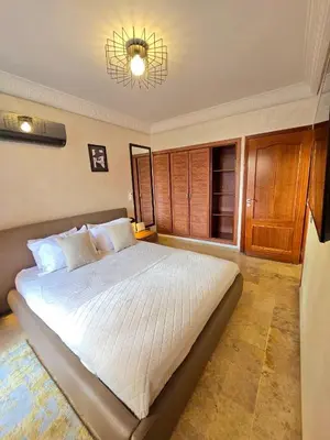 a bedroom with a large white bed with a chandelier at Joli et chic Appartement à Marrakech - balcon privé et confort in Oulad Akkou