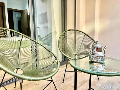 two green chairs and a glass table on a balcony at Résidence Ménara Garden Proche Gare & Jardins Ménara in Marrakech