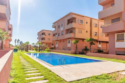 an apartment with a swimming pool in front of a building at Appartement calme et ensoleillé avec piscine in Marrakech