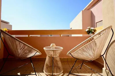 two chairs and a table on a balcony at Appartement calme et ensoleillé avec piscine in Marrakech