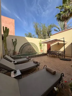 a patio with couches and umbrellas in front of a building at Luxury Private Riad, Air-Conditioned and Pool in Marrakech