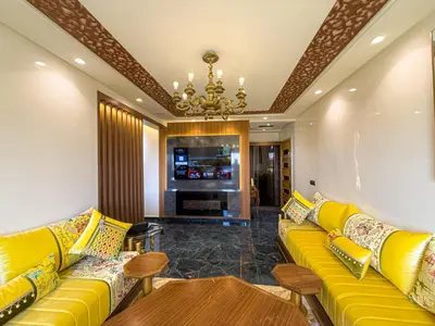 a living room with yellow couches and a tv at Essalmi Luxury Apartment in Marrakech in Marrakech