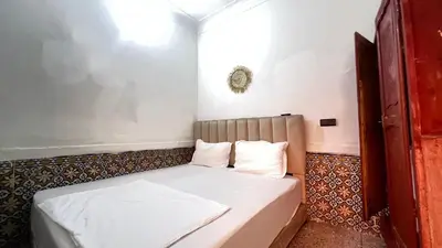 a small room with a bed with white sheets at Riad Nomad in Marrakech