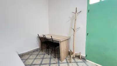 a table and chairs in a room with a wall at Riad Nomad in Marrakech