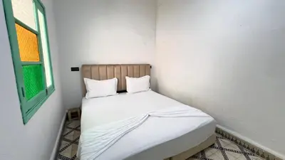 a small bedroom with a bed with white sheets and a window at Riad Nomad in Marrakech