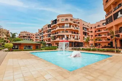 a swimming pool with a fountain in front of a building at Luxe et sérénité avec jardin, terrasse et 5 piscines in Marrakech