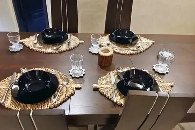 a wooden table with black plates and napkins on at Luxe et sérénité avec jardin, terrasse et 5 piscines in Marrakech