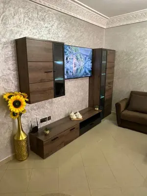 a living room with a television and a vase with a flower at Exceptionnel appartement a louer in Marrakech