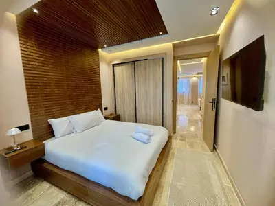 a bedroom with a white bed and a television at Gueliz Terracotta Stay - 2 BR & Cozy Balcony in Marrakech