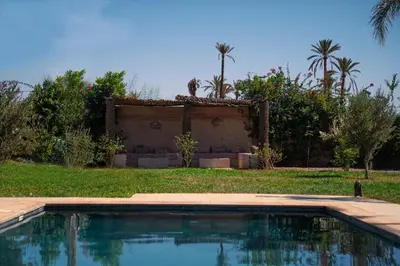 a swimming pool in front of a yard with palm trees at Viva La Villa in Marrakech