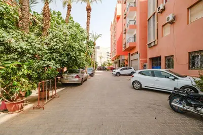a city street with parked cars and palm trees at Charmant appartement lumineux pres de Gueliz. in Marrakech