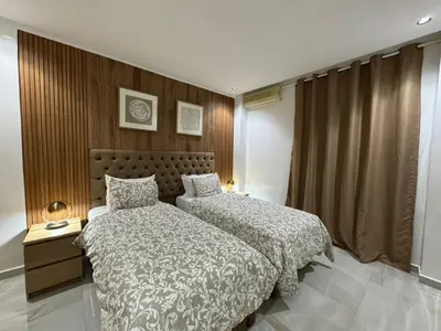a bedroom with two beds and a wooden wall at Duplex Menara Mall in Marrakech